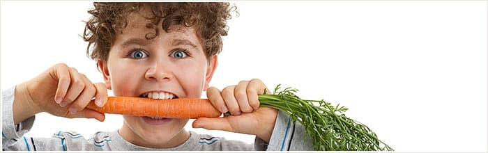 Young child biting into a carrot